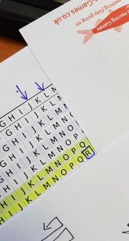 A Red Herring Games sheet part-covering a highlighted Vigenère square on a desk