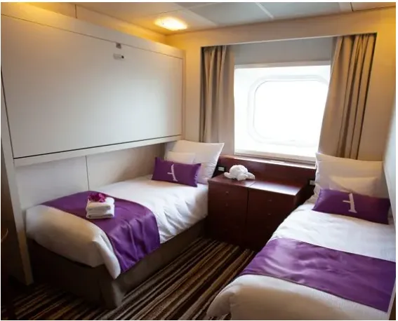 An Ocean View twin cabin aboard the Ambassador, with a porthole window